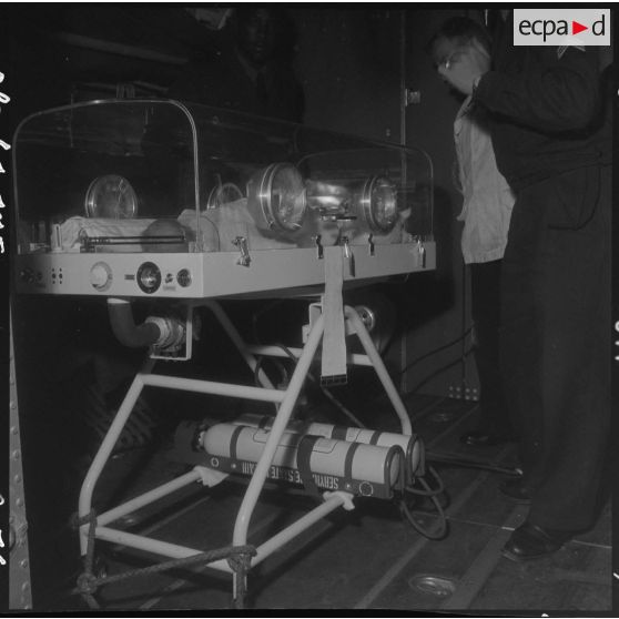 Maison Blanche. Embarquement et installation du berceau d'incubation avec le bébé à bord de l'avion Nord-2501 Noratlas.