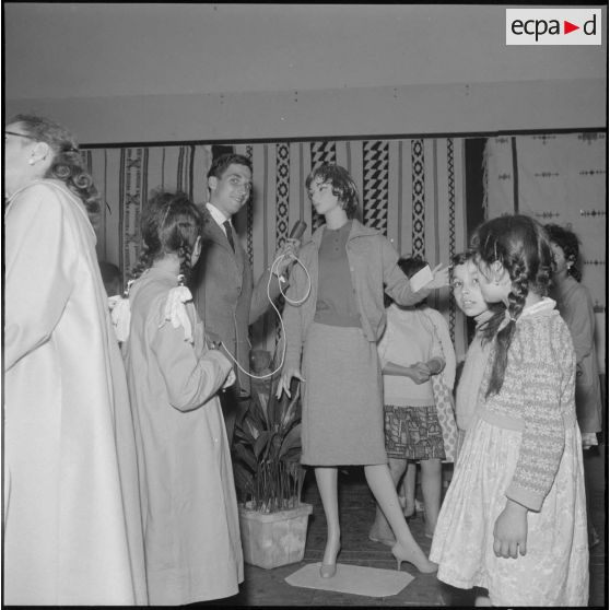 Alger. Salle Pierre Bordes. Vente de la production des cercles de solidarité féminine de l'Algérois. Un reporter de la Voix du Bled dans l'exercice de ses fonctions.