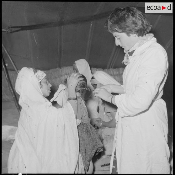 Un membre de l'équipe médico-sociale itinérante (E.M.S.I.), coiffant une petite fille.