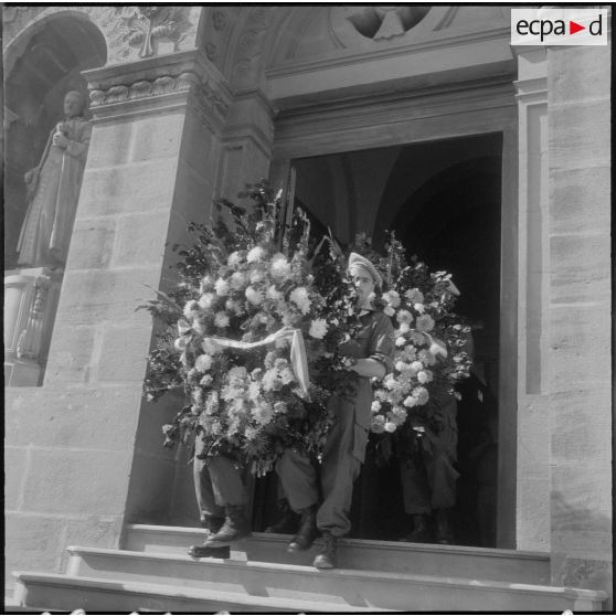 Des militaires, appartenant au 27e dragon, portant des gerbes de fleurs sur leurs épaules.