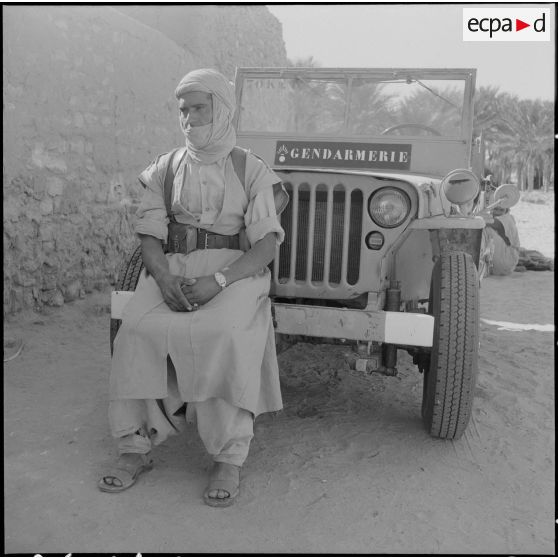 Bir el Adal. Cérémonie de l'échange des montures. Portrait d'un méhariste à bord d'une jeep de gendarmerie.