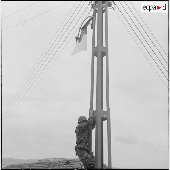 Alger. Belcourt. Un soldat grimpe sur un poteau électrique où le drapeau du Front de libération national (FLN) a été accroché.
