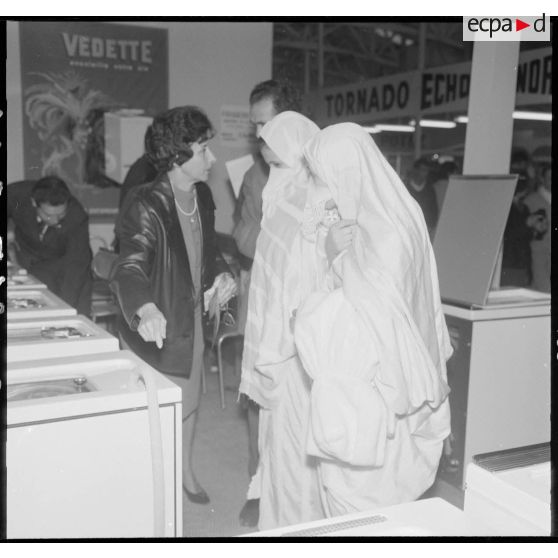Alger. Exposition d'électroménager. Deux jeunes femmes se font expliquer les caractéristiques de l'un des nombreux modèles de machines à laver exposées.