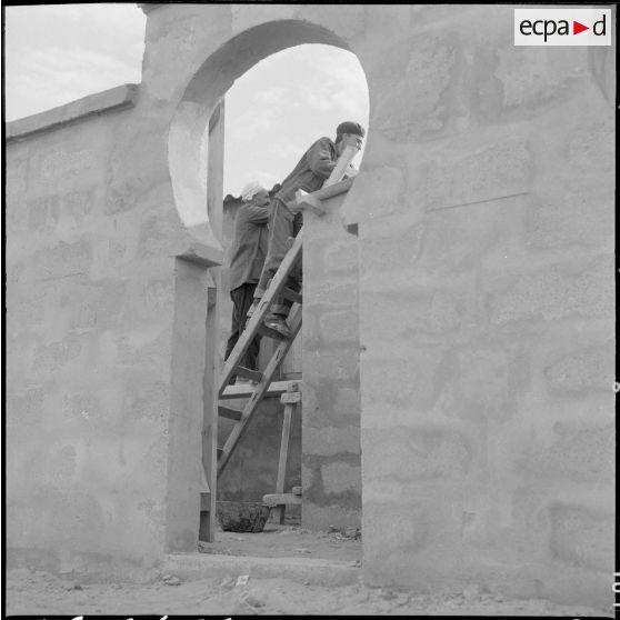 Sidi Salem. A travers une entrée, un ouvrier termine un logement.