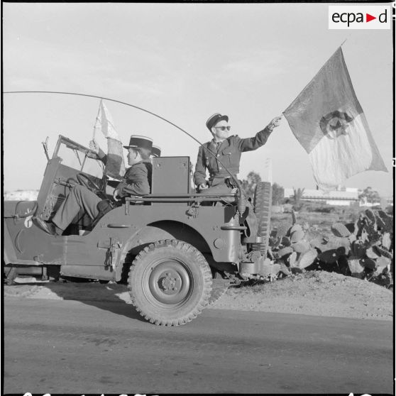 Bône. Manifestations. Un soldat agite le drapeau du Front de libération national (FLN) à bord d'une jeep.