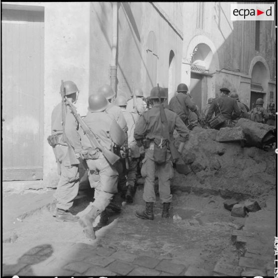 Bône. Manifestations. Des soldats franchissent une barricade.