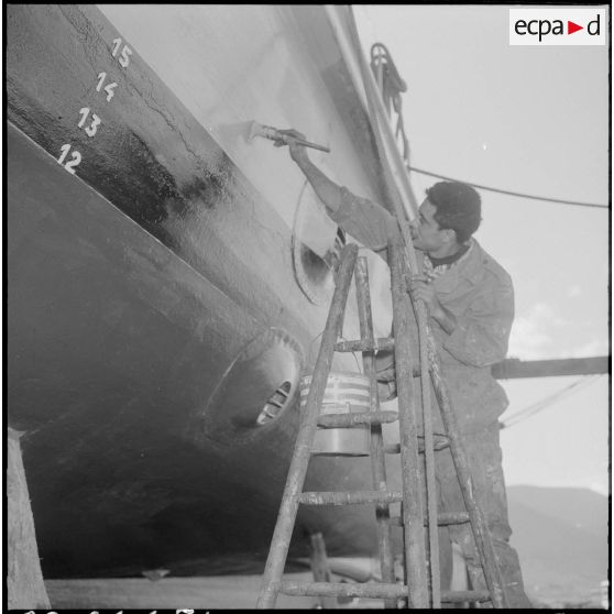Mers el-Kébir. Les ouvriers repeignent la coque de la vedette côtière P755 à l'aide de panneaux et de rouleaux.