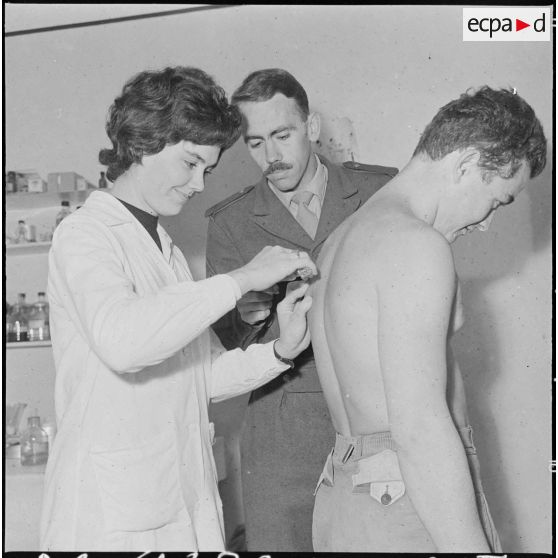 Attention à la piqûre. Sous l'oeil de l'infirmier, cette membre des équipes médico-sociales itinérantes (EMSI)  fait une piqûre.