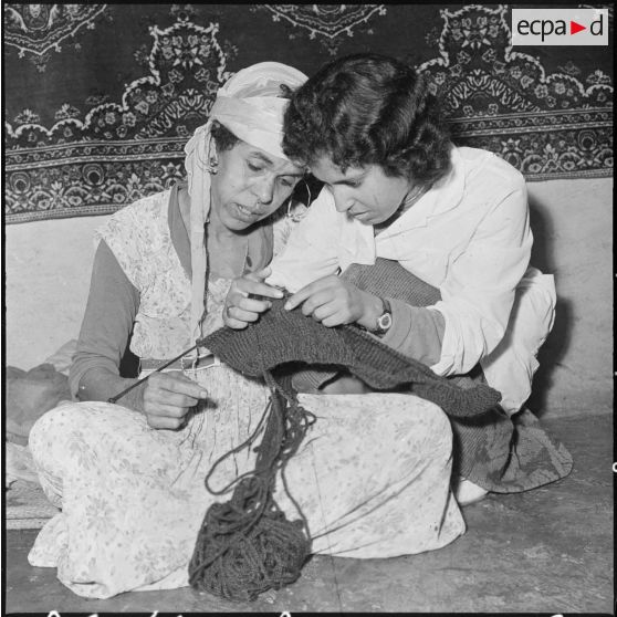 Une membre des équipes médico-sociales itinérantes (EMSI) montre à une femme comment tricoter.