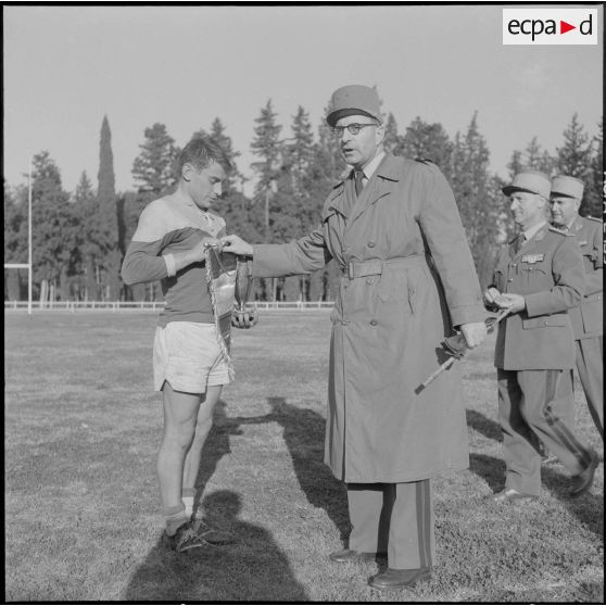 Finale des championnats militaires de rugby à XV des forces terrestres en Algérie. Le général Menard remet la coupe et le fanion au capitaine de l'équipe de la CRT n°10 (compagnie régionale du train).