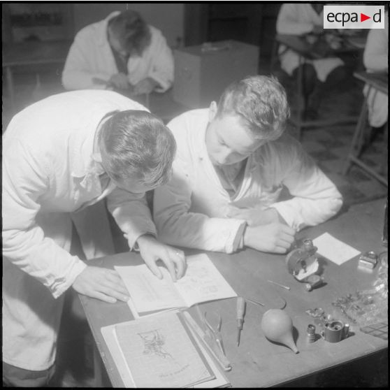Camp de L'Alma (camp Bonvalot). Centre d'instruction du service du matériel n°3 (CISM n° 3). Un soldat travaillant sur des pièces en cours d'optique en suivant les conseils d'instructeur.