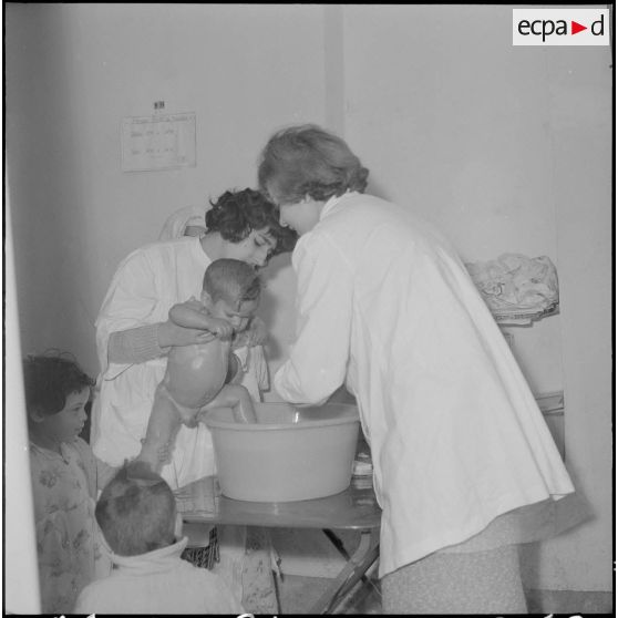 Aïn Temouchent. Une membre de l'équipe médico-sociale itinérante montre à une mère comment faire la toilette de son bébé.