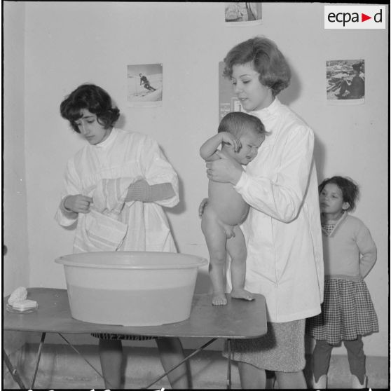Aïn Temouchent. Une membre de l'équipe médico-sociale itinérante montre à une mère comment faire la toilette de son bébé.