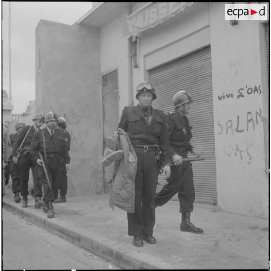 Oran. Fouilles et récupérations d'armes de l'Organisation armée secrète (OAS). Des gendarmes mobiles patrouillent dans une rue.