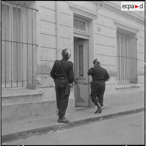 Oran. Fouilles et récupérations d'armes de l'Organisation armée secrète (OAS). Deux gendarmes mobiles fouillent un immeuble.
