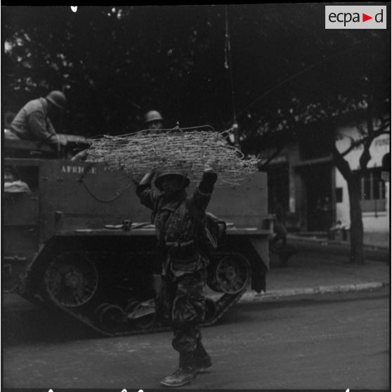 Bouclage d'Oran. Un soldat transporte des barbelés.