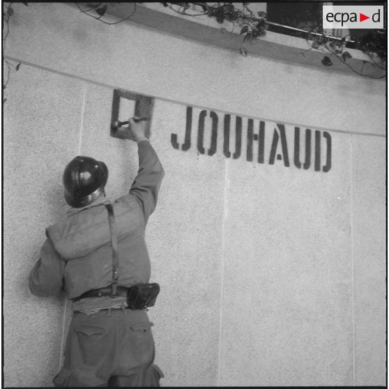 Oran. Mise en place des troupes sur les terrasses. Un soldat repeint l'inscription "Le Jouhaud" sur un immeuble.