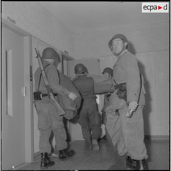 Oran. Mise en place des troupes sur les terrasses. Des soldats chargent des sacs dans un ascenseur.