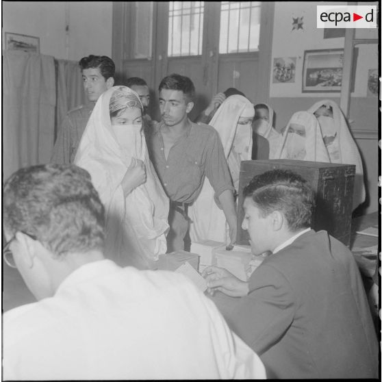 Journée de vote pour le référendum d'autodétermination (1er juillet 1962). Un assesseur vérifie les papiers d'identités d'une femme au bureau de vote n°1.