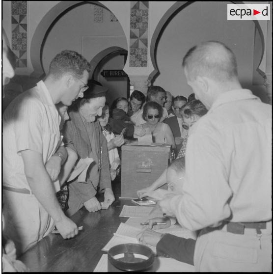 Journée de vote pour le référendum d'autodétermination (1er juillet 1962). Des assesseurs vérifient les identités des votants à l'intéieur d'un bureau de vote.
