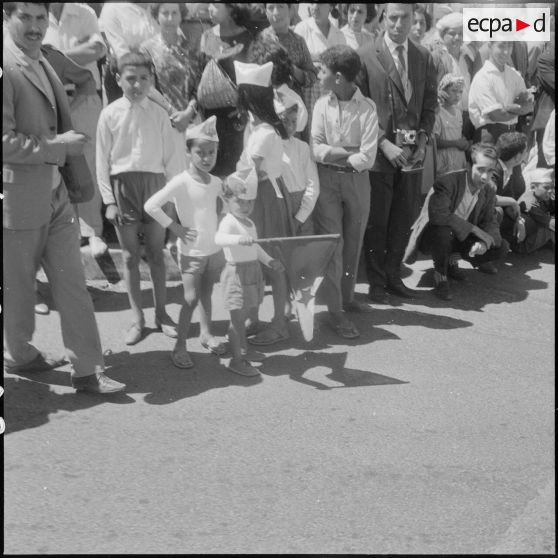 Un garçon parmi la foule brandissant un drapeau algérien pour la cérémonie de lever des couleurs algériennes.