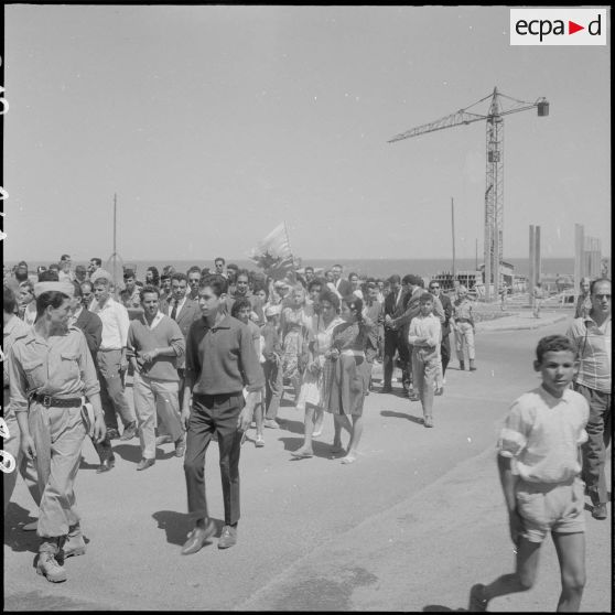 Des civils se préparent pour la cérémonie de lever des couleurs algériennes.