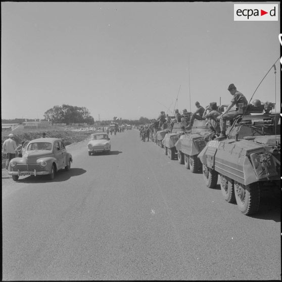 Des soldats de l'armée française à bord d'automitrailleuses Light armored car M8 regardent la population algérienne fêter leur indépendance dans les rues d'Alger.