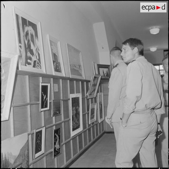 Des officiers visitent une exposition de peinture à la base aérienne 210 (BA 210).