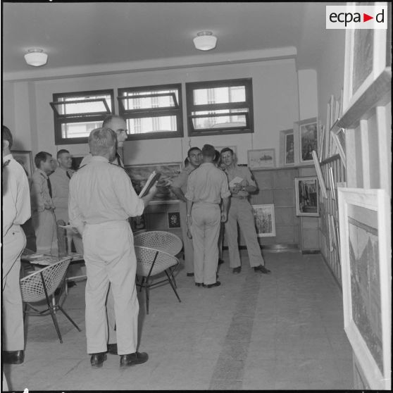 Des officiers visitent une exposition de peinture à la base aérienne 210 (BA 210).