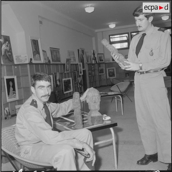 Des officiers visitent une exposition de peinture à la base aérienne 210 (BA 210).