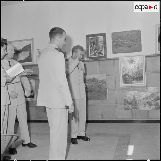 Des officiers visitent une exposition de peinture à la base aérienne 210 (BA 210).