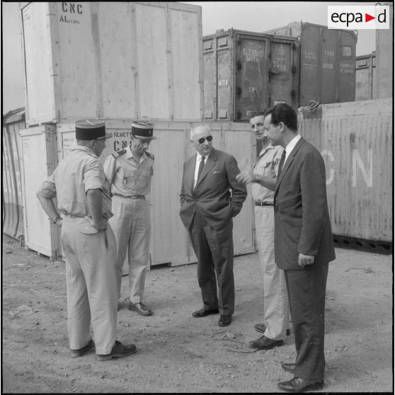 Des directeurs de l'entreprise Danzas et Tailleur s'entretiennent avec des militaires au milieu de containers au port d'Oran.