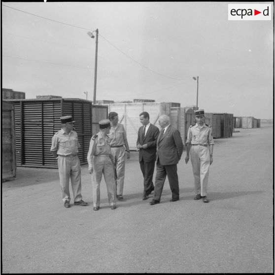 Des directeurs de l'entreprise Danzas et Tailleur marchent au milieu de containers au port d'Oran avec des militaires.
