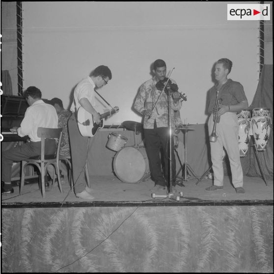 Groupe théâtral de Blida se produisant sur la scène du cinéma de La Reghaïa. Concert de musiciens sur scène.