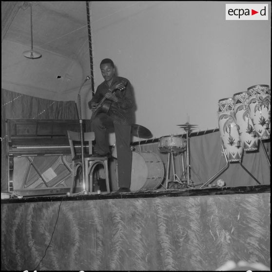 Groupe théâtral de Blida se produisant sur la scène du cinéma de La Reghaïa. Un musicien joue de la guitare sur scène.