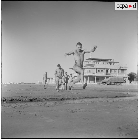 Activités sportives d'une section du 152e régiment d'infanterie (RI). Un soldat saute par dessus un courant d'eau sur la plage.