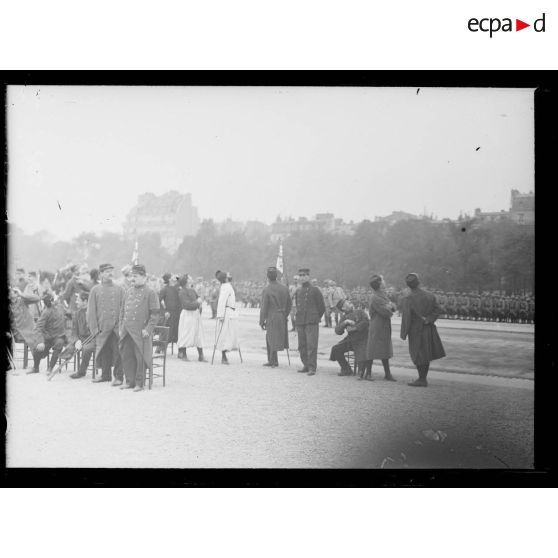 Remise de drapeaux aux Invalides aux régiments d'infanterie territoriale (230e-237e RIT). Les blessés regardent passer les aéros. [légende d'origine]
