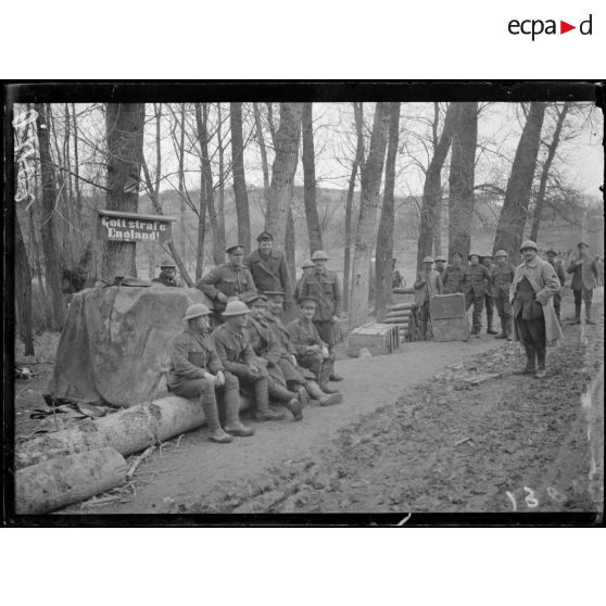 [Des soldats et des autorités militaires, assises sur un tronc d'arbre, sont réunis sous une pancarte sur laquelle est inscrit "Gott strafe England !".]