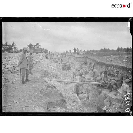 [Des soldats creusent un terrain rocheux, sous le regard d'autorités militaires.]