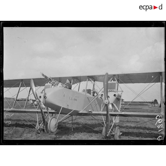 [Un avion militaire équipé de mitrailleuses sur un camp d'aviation.]