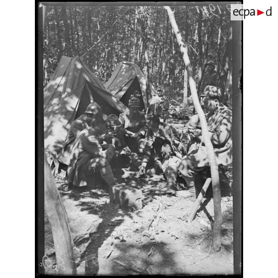 [Scène de la vie quotidienne dans un campement italien, en pleine forêt, dans la Marne : un groupe de soldats joue aux cartes devant une tente.]