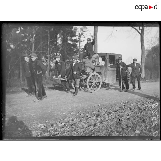 [Une voiture hippomobile tractée par quatre hommes, sur une route de campagne.]