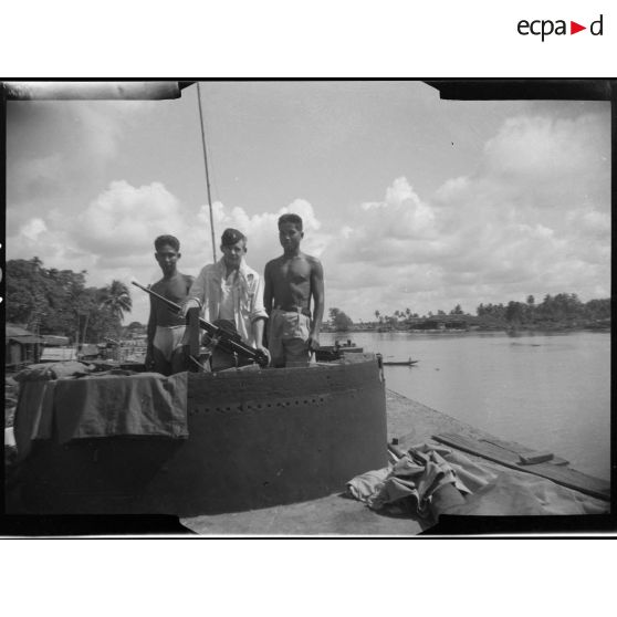 1 à 3 Un tireur sur une mitrailleuse Reibel M31 avec 2 coéquipiers surveille un convoi fluvial de marchandises. [description provisoire]