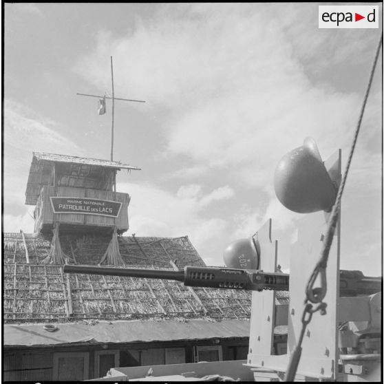 Le bâtiment de la patrouille des Lacs. Au premier plan, un canon Oerlikon MkIV de 20mm d'une vedette de patrouille (VP). [description provisoire]