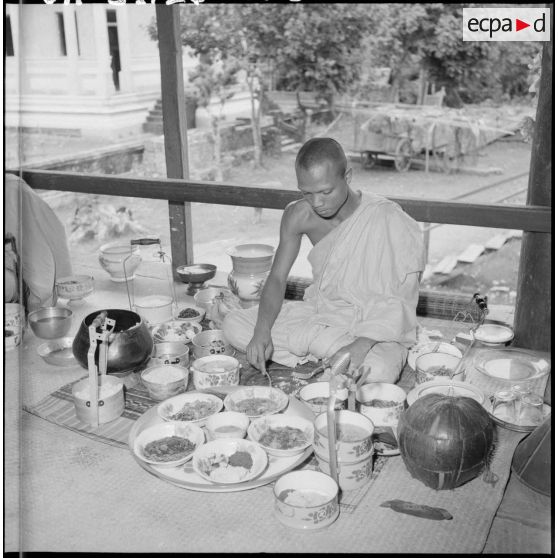 Repas rituel des bonzes dans la salle des fêtes auquel assistent les fidèles. [description provisoire]