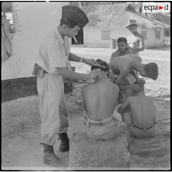 10 3 militaires cambodgiens coupent les cheveux de militaires dans une cour. [description provisoire]
