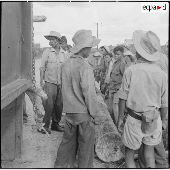 12 à 16 Corvée de chargement de billots de bois à bord de GMC 6X6 par des militaires de l'armée cambodgienne. [description provisoire]