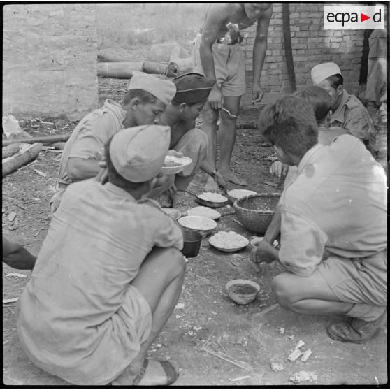 2 4 militaires prennent leur repas, à base de riz et de poisson sec. [description provisoire]