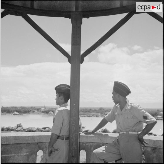 15 Plan américain de deux militaires cambodgiens vus de profil sur la plate-forme du minaret qui surplombe une rivière. [description provisoire]