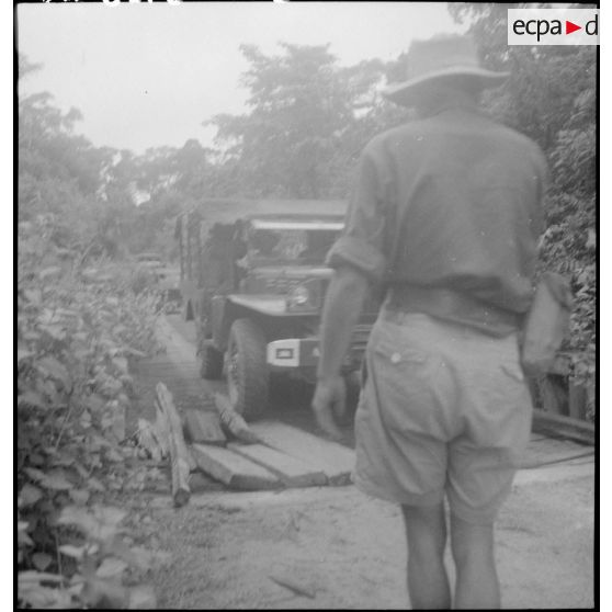 5 L'adjudant Marine guide le passage l'un des camions GMC 6 X 6 du convoi sur un pont de planches. [description provisoire]